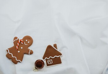 Gingerbread cookies in the shape of a gingerbread man and a house, decorated with icing