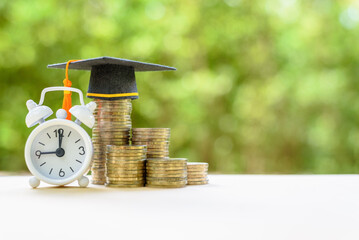 Investing in education: Balancing time and financial resources. Coins, a graduation cap and a...