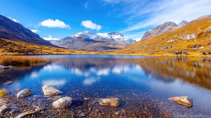 Obraz premium Calm lake reflecting mountains under a blue sky.