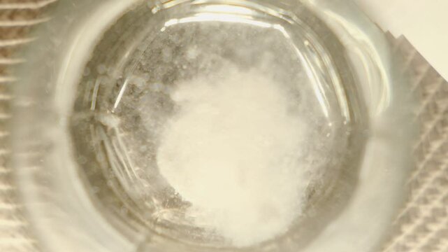 Effervescent, soluble tablet or vitamin supplement falling into glass of water, close-up