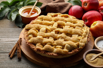 Tasty homemade apple pie and ingredients on wooden table, closeup