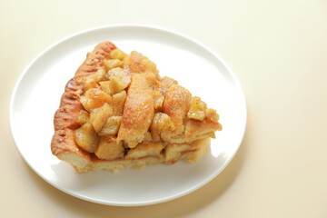 Slice of homemade apple pie on beige background, closeup