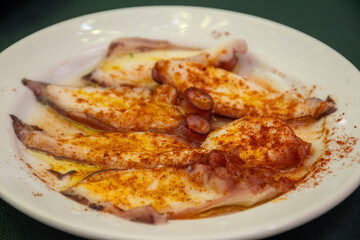 Traditional andalusian dish pulpo octopus  seafood served with red pimento paprika  in old tavern as tapas, Sanlucar de Barrameda, Spain