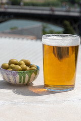 Spanish beer and bowl with green andalusian olives served on outdoor roof terrace with view on central part of old Sevilla, Andalusia, Spain