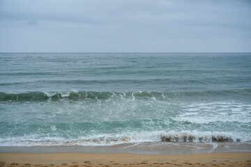 Scenic view of ocean waves crashing on a sandy beach. The tranquil scene evokes a sense of peace and relaxation, perfect for travel or nature-themed projects.