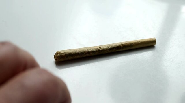 Fingers tapping nervously next to cannabis joint