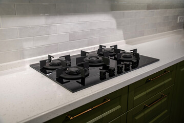 Modern black glass gas stove on stone countertop