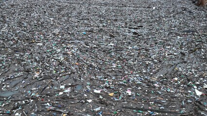 Dirty river, polluted with waste, destroyed environment and nature, plastic and tires
