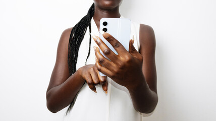 Young black african woman in white sleeveless shirt holding in hand mobile cell phone surfing...
