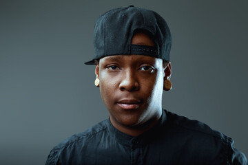 Young man with plugs and baseball cap staring at camera