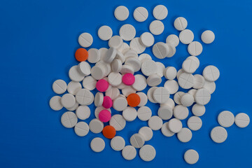 Assorted pills and tablets scattered on a vibrant blue surface