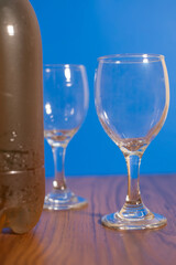Glasses and bottle of wine on a wooden table with a blue background