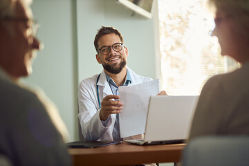 Happy male doctor talking with his patients while having an appointment in the office.