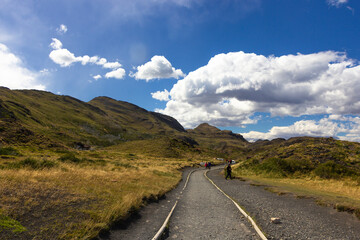 camino de tierra bajo un cielo azul con nubes, en Parque Nacional Torres del Paine, Patagonia, Región de Magallanes y Antártica chilena, Chile