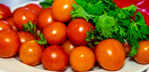 Fresh cherry tomatoes with cilantro and peppers on a white plate in a kitchen