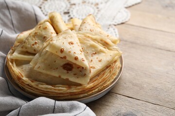 Delicious folded crepes on wooden table, closeup. Space for text