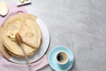 Tasty crepes with butter and honey served on grey textured table, flat lay. Space for text