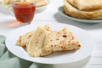 Tasty crepes on white wooden table, closeup
