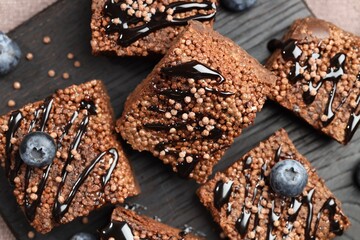 Delicious chocolate puffed rice bars and blueberries on table, top view
