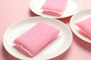 Sponges and plates on pink background, closeup