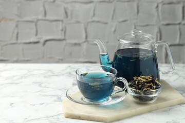 Delicious butterfly pea flower tea on white marble table against light background, space for text