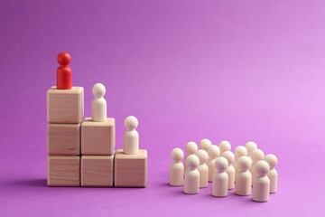 Human figures, red one on top of stacked wooden cubes against violet background. Competition concept