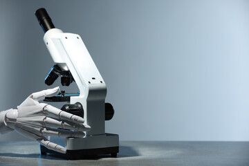 Artificial intelligence. Robot hand working with microscope at table against light grey background, space for text