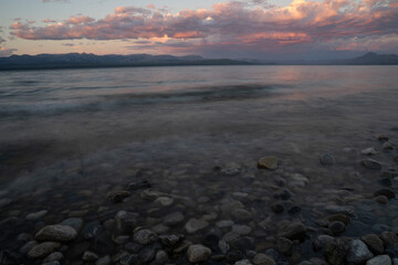 Obraz premium Long exposure shot of Nahuel Huapi lake at sunset. Beautiful blurred water effect, the rocky shore and dusk colors
