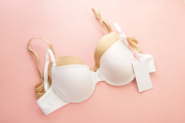 Women's bras with white paper labels on pink background