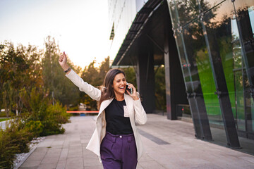 Excited businesswoman talking on a phone after work