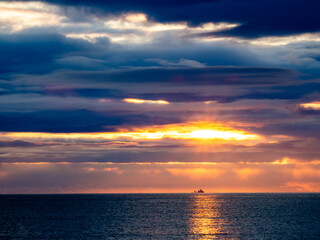Fototapeta premium Ocean going vessel on horizon with beautiful sunrise