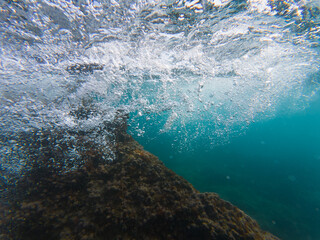 Obraz premium Underwater shot of a wave breaking on rocks in the French Riviera.