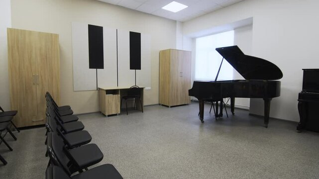 Grand piano stands near window in small concert hall. Soft lighting and contrasting tones create environment suited for music along with presentations