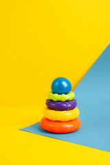 Kids toy, pyramid tower made of colorful plastic rings. Rainbow ring tower on a colorful background