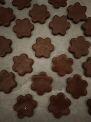 Freshly baked chocolate flower shaped cookies cooling on baking paper christmas time