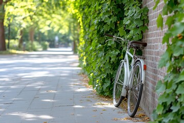 Naklejka premium Vintage bicycle leaning against brick wall in park. Sunlight, pathway, lush green foliage, summer, outdoor, urban, transportation, pedestrian, environment, calm, quiet, peaceful, vacation, 
