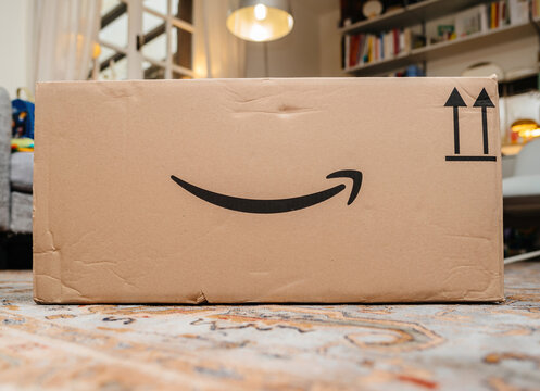 Paris, France - Dec 1, 2024: A large Amazon box featuring the iconic smile logo, placed indoors, showcasing delivery, logistics, and branded packaging