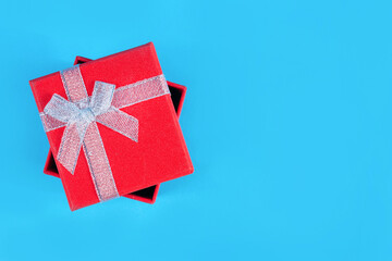 Top view of a red gift box with a tied ribbon on a classic blue background in a studio. Christmas or Valentine's Day concept with copy space for text or design