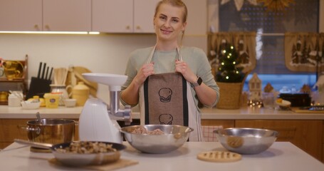 Woman smiles in kitchen background while working preparing holiday dishes