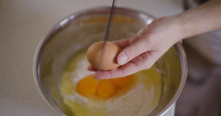 Close-up of cracking raw egg into bowl breaking egg with knife