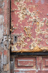 Close up of a weathered wooden door with peeling paint, rust, and decay, showcasing textures of deterioration and aging on an old structure, deteriorated wood texture, vertical