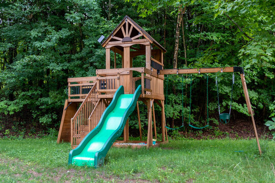 Wooden Playground With Slide And Swings In The Woods