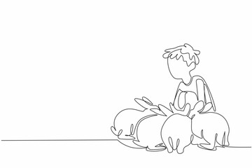 Single one line drawing boy is squatting and surrounded by many rabbits. It is time to feed the beloved livestock. Learn to farm. National Farm Animals Day. Continuous line design graphic illustration