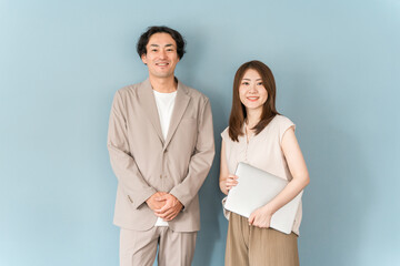 オフィスでノートパソコンを持って立つ男女のビジネスマン
