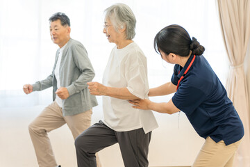 デイサービスで運動するシニアの男女と理学療法士・作業療法士・ケアマネージャーの女性