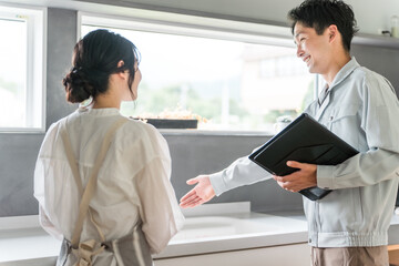 キッチンで主婦に水道屋・設備の説明をする水道屋・設備屋の男性
