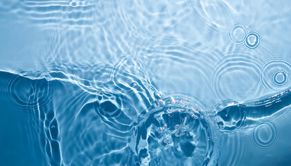 Blurred transparent blue colored clear calm water surface texture with splashes and bubbles. Trendy abstract nature background. Water waves in sunlight with copy space.
