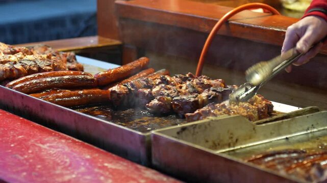 Street vendor grilling traditional Polish sausages and meat skewers at Christmas market in Wroclaw. Concept of festive street food, winter traditions, local culinary delights. High quality 4k footage