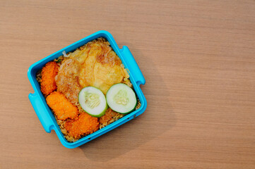 fried rice in a food box with side dishes of fried egg and nuggets