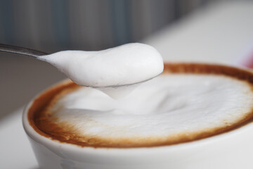 Enjoy a Creamy Coffee Cup with Frothy Milk and a Spoon, ideal for cozy mornings